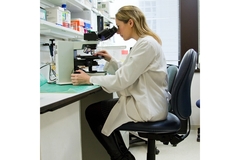Image A women looks in a microscope.